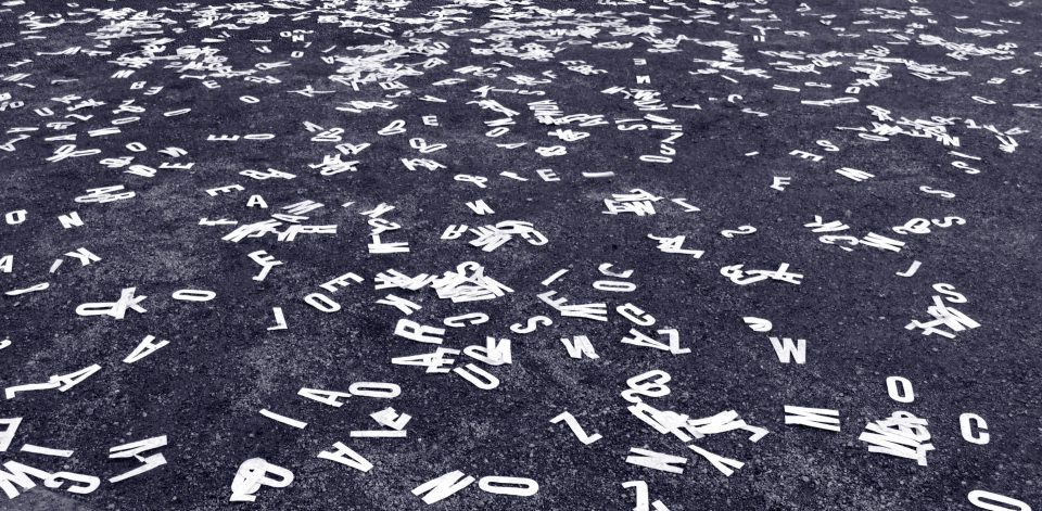 black and white photo of white letter cut-outs strewn on pavement