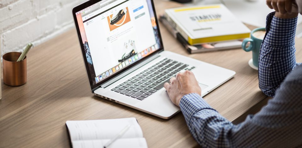 closeup photo of man's arm typing on a laptop